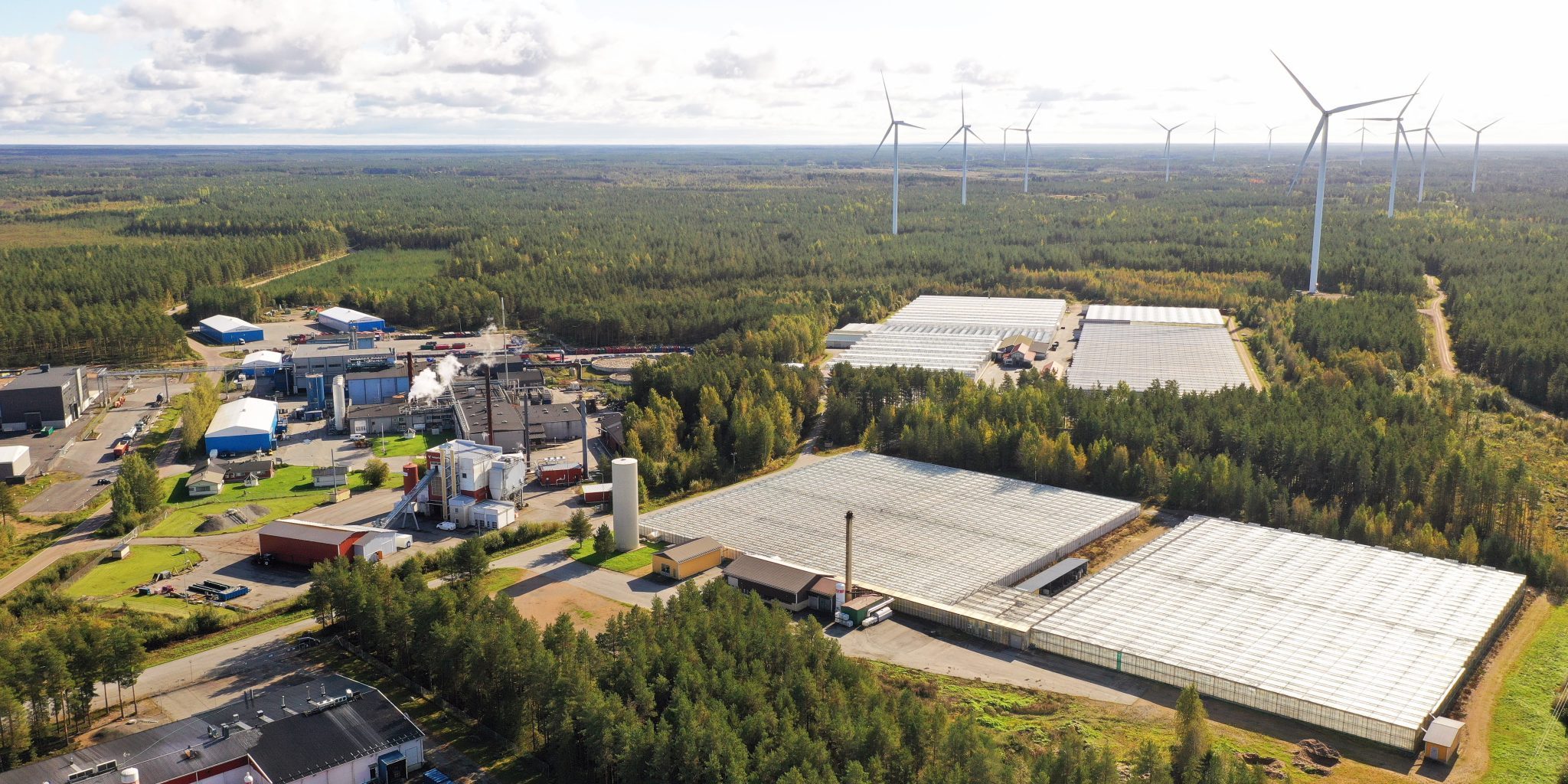 Ilmakuvaa Kirkkokallion alueelta, jossa näkyy kauempana tuulivoimalaa ja isoja teollisuusrakennuksia.